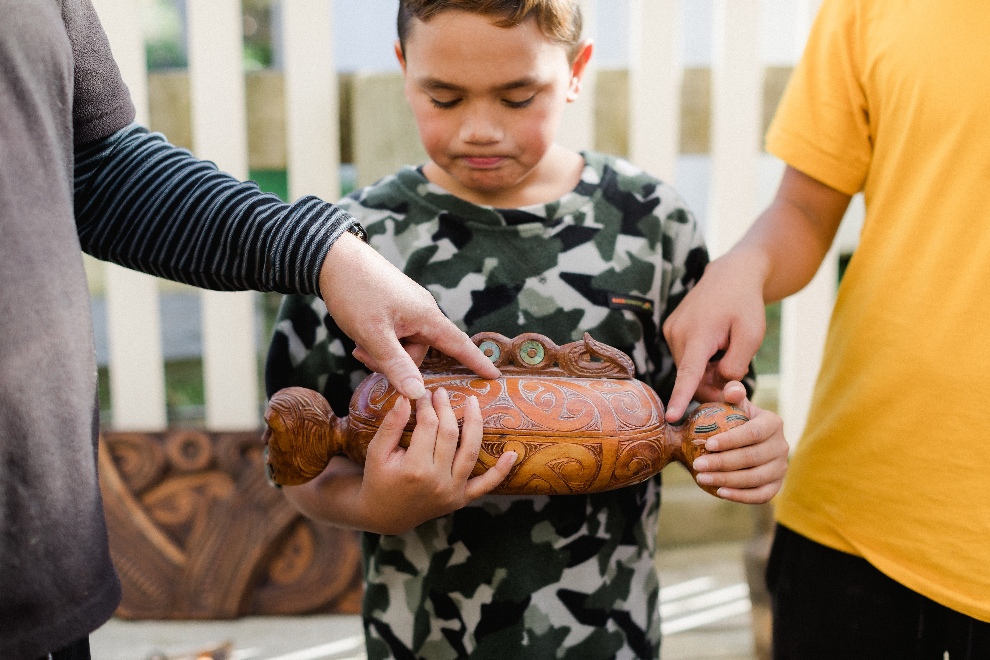 child holding a maori carving